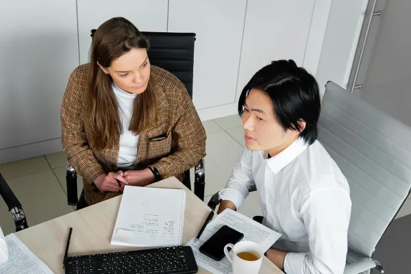 Two people sitting at a table with documents
